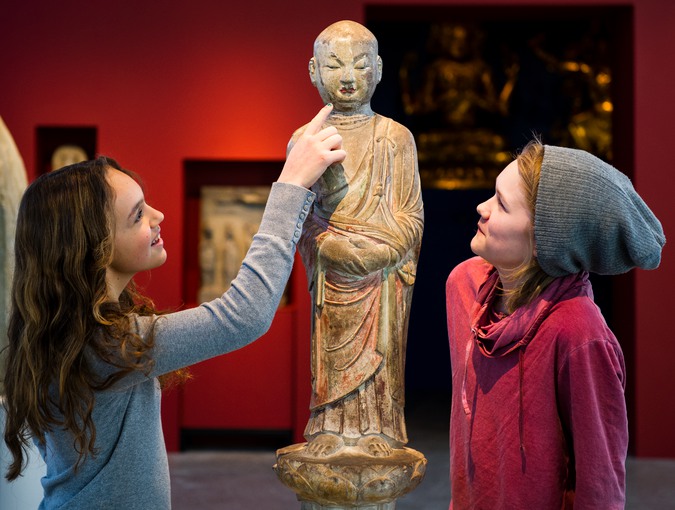 Två tjejer kollar på en staty. Fotografi.